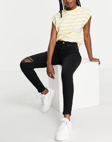 Jeans skinny a vita super alta in nero con strappi - Stradivarius - Modalova